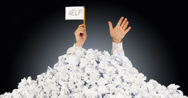 two hands reaching up out of a pile of paper with a white flag that reads "help"