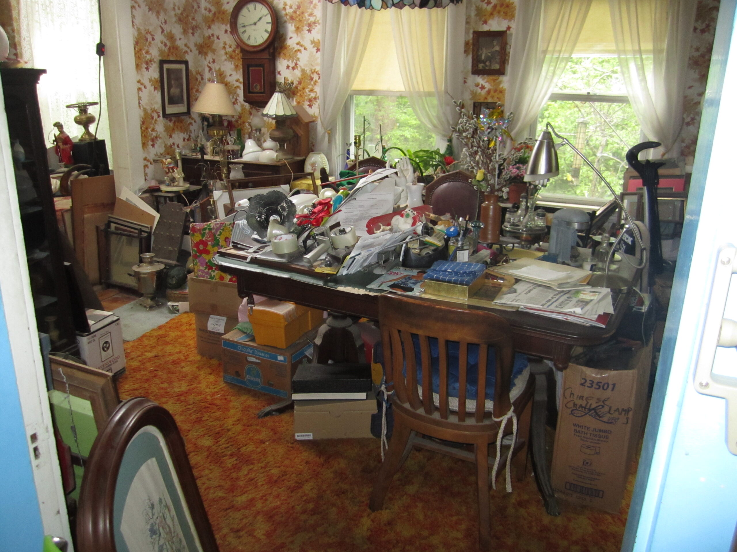 help with downsizing before photo of a dining room with clutter all over table and shelves