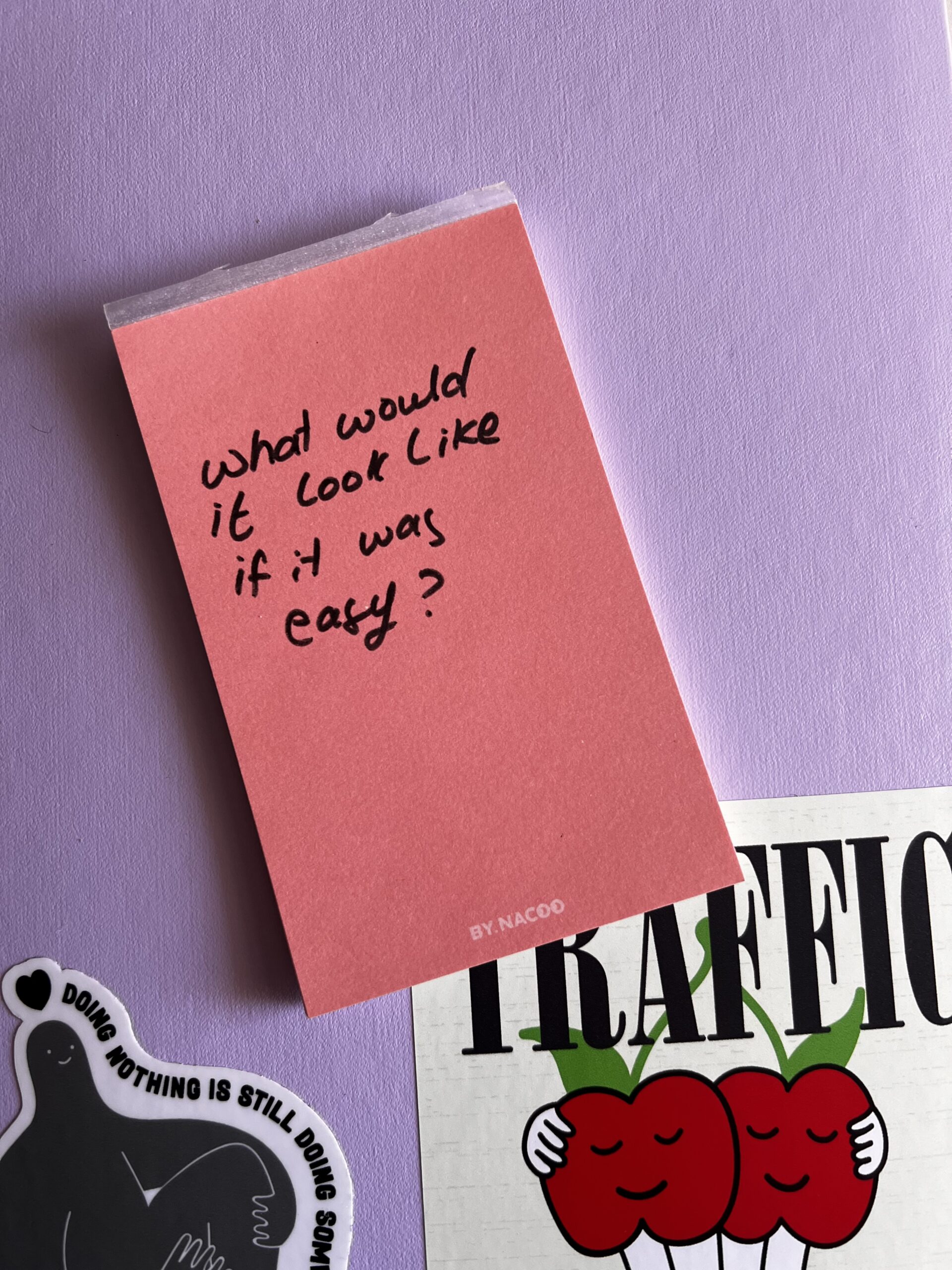 ula-kaniuch-dupe Close-up of a pink sticky note with handwritten question 'What would it look like if it was easy?' on a purple surface.